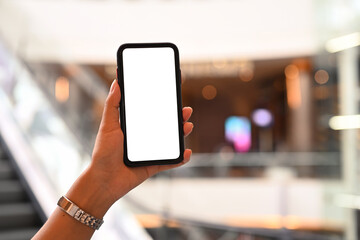 Woman hand holding mock up smart phone against blurred escalator background. Empty screen for your advertise text