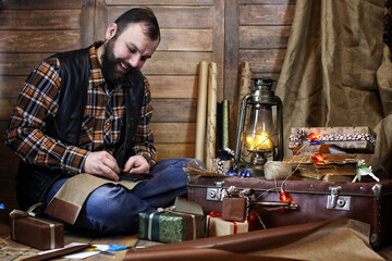 bearded man in shirt and vest packs Christmas gifts posing at camera
