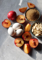 Sweet cake ingredients on a table. Close up photo of plums, eggs, brown sugar and almonds. Baking  fruit pie. Healthy eating concept. 