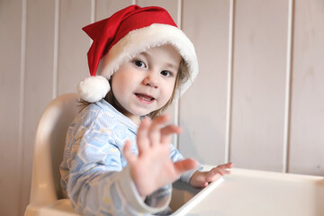 A small child in a santa hat sits in a chair