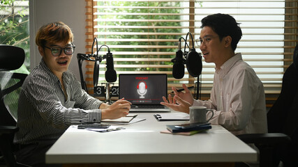 Shot of male radio host discussing various topics with guest during streaming live audio podcast from home studio