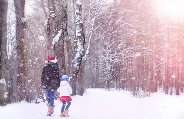 A winter fairy tale, a young mother and her daughter ride a sled in the forest. A girl on a sled with gifts on the eve of the new year in the park. 