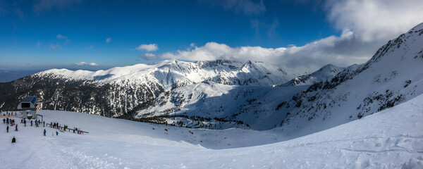 Panoramic winter landscape of Todorka 2 ski lift station and Tipizite peaks ubder blue sky....