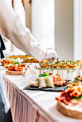 woman hands of a waiter prepare food for a buffet table in a restaurant