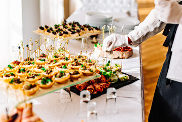 woman hands of a waiter prepare food for a buffet table in a restaurant