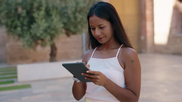 Young beautiful woman smiling confident using touchpad at street