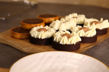 Tart set with meringue on a dark background. Side view, top view. Professional dessert. Coconut filling, coco inside the tart, chocolate filling. Several tarts on a wooden tray.