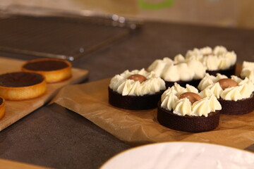 Tart set with meringue on a dark background. Side view, top view. Professional dessert. Coconut filling, coco inside the tart, chocolate filling. Several tarts on a wooden tray.