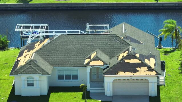 Damaged house roof with missing shingles after hurricane Ian in Florida. Consequences of natural disaster