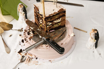 Finished wedding cake. Wedding cake leftovers with knives laying on top. Half-eaten wedding cake....