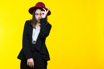 Fototapeta premium Brunette in a suit and hat on a yellow background.
