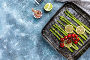 Fototapeta na wymiar baked green asparagus stalks with lemon and cherry tomatoes, Healthy food, diet menu. banner, menu, recipe place for text, top view