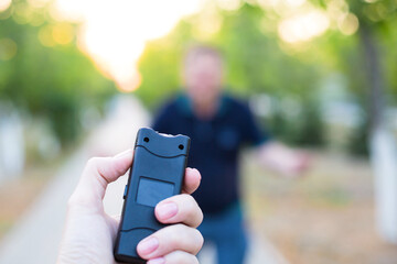 A stun gun in a woman's hand, protection from an attacking man.
