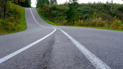 Asphalted country road with two white stripes. a bend in the road with a mountain
