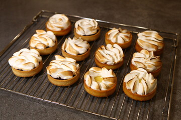 The tart cooking process, dessert in the oven, baking of tarts. Side view, top view. Professional dessert-making process. After baking dark and baked meringue.