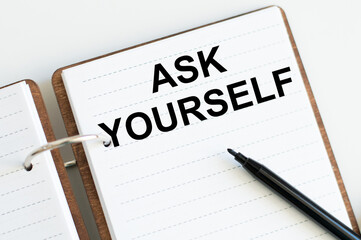 Ask Yourself inscription on the notepad on the table next to the black marker