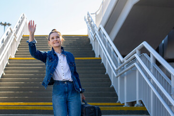  woman waves goodbye. A young woman says goodbye by waving her hand.