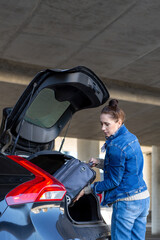 woman is packing a suitcase in the trunk of a car