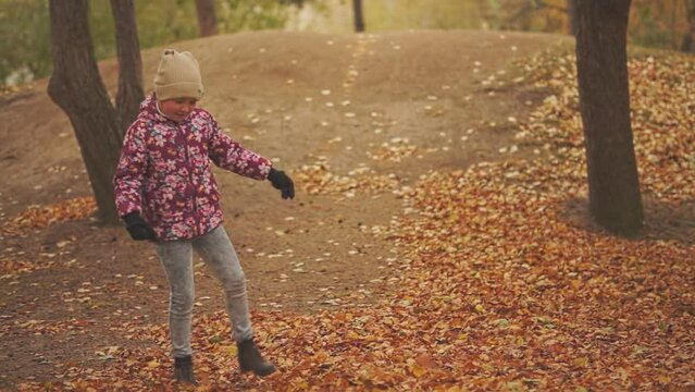 a child in the park kicks yellow and orange fallen leaves