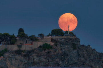 almuñecar, spain, a large full moon rising over the rocks of the peñon de san francisco also...