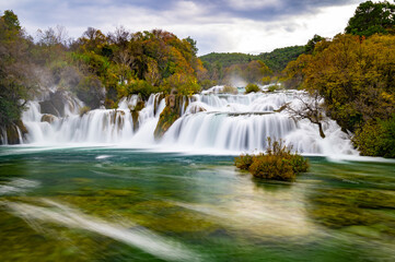 Krka National Park during colorful autumn travel destination in Dalmatia, Croatia, Europe. Fall colors leafs on trees. Krka Waterfalls and water in sunny morning light with fog. Landscape photography.