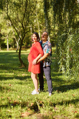 Fototapeta premium Lovely pregnant couple walking in a park