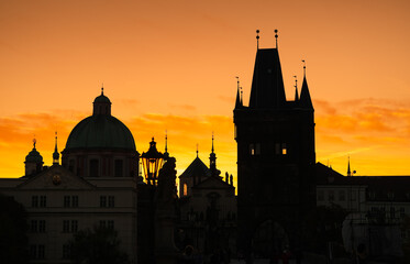 Fototapeta premium Spectacular sunrise in Prague, sun rising between the landmark towers from Charles Bridge during an unique autumn moment. Travel to Czech Republic.