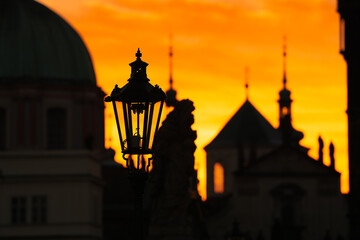 Fototapeta premium Spectacular sunrise in Prague, sun rising between the landmark towers from Charles Bridge during an unique autumn moment. Travel to Czech Republic.