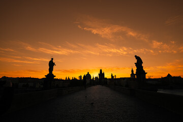 Fototapeta na wymiar Spectacular sunrise in Prague, sun rising between the landmark towers from Charles Bridge during an unique autumn moment. Travel to Czech Republic.