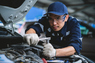 Portrait of an Asian mechanic checking the safety of a car. Maintenance of damaged parts in the garage. Maintenance repairs. Repair service concept.