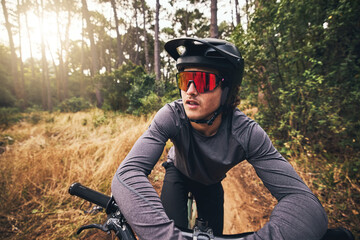Cyclist, bike and forest on adventure in nature for health, fitness and wellness. Man, bicycle and sunglasses in woods for travel with helmet on training, exercise or workout on trail by trees