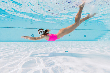 Attractive woman in pink swimwear dive and swimming underwater in pool