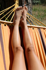 slender legs of the young girl resting on the hammock