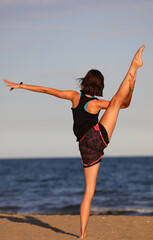 young slim athletic girl performs gymnastic exercises in summer