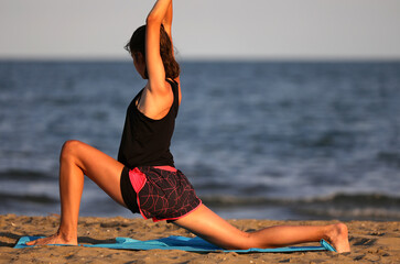 Fototapeta na wymiar slender girl does gymnastic exercises at the beach