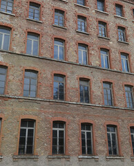 Fototapeta na wymiar red bricks and old peeling windows of an old industrial building