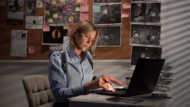 Detective working at desk in her office using laptop computer, investigator processing evidence