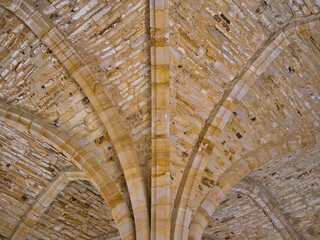 Columns and stonework in a Gothic limestone vaulted ceiling.