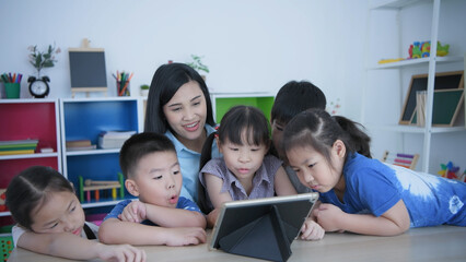Fototapeta premium Educational concept of 4k Resolution. kindergarten teacher teaching children using tablet in classroom.