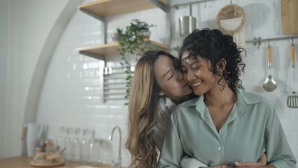 Fototapeta premium Holiday concept of 4k Resolution. Asian women embracing each other in the kitchen. Young women are in a mutual lesbian love relationship.