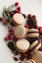 Chocolate Macaron (French Macaroon) with ganache filling on a table with mint and bars of chocolate and nuts. Food composition.