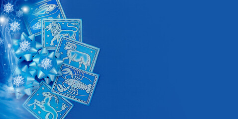 blue astrological christmas background with copy space a few zodiac signs and xmass gift decorations, white snowflakes and lights 