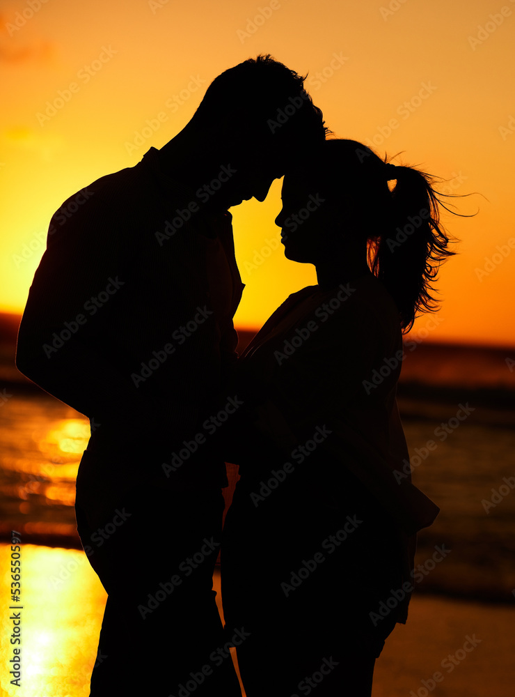 Poster Silhouette of young couple on the beach at sunset embracing each other in affection. People on holiday, vacation and honeymoon by the ocean. Intimate, love and romantic man and woman together by sea