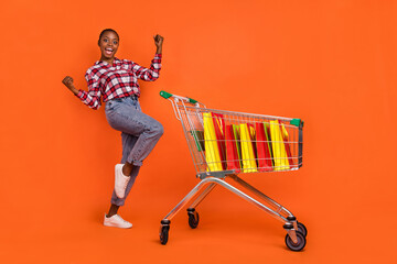 Full size portrait of excited crazy person raise fists celebrate triumph isolated on orange color...