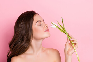 Obraz na płótnie Canvas Photo of adorable dreamy young woman naked shoulders smelling flower bloom closes eyes isolated pink color background