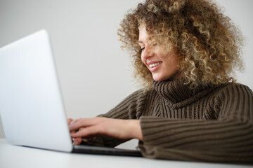 Happy white woman typing text on laptop keyboard. Cheerful Ukrainian female person working on notebook computer