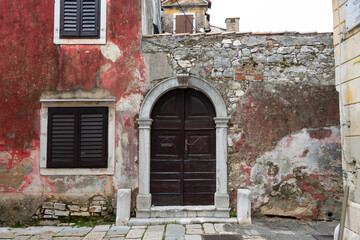 An old doorway next to a red wall in Porec, Istria, Croatia.