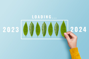 Hand putting leaf for countdown to 2024. Loading year 2023 to 2024. Start concept