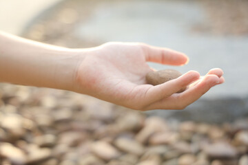 female hand holding small pebble stones picking up pebbles, round shape pebbles, summer vacation souvenir,