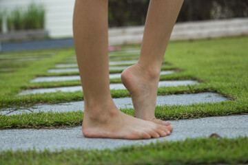A barefoot little girl walks along the path in the garden.